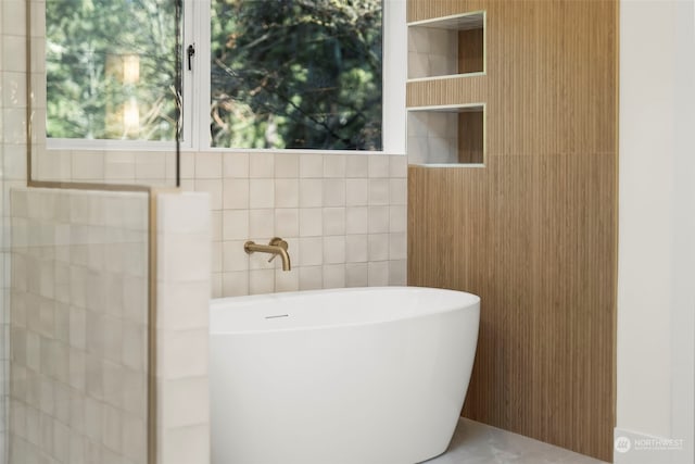 bathroom featuring a freestanding bath and tile walls