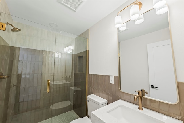 bathroom with a stall shower, visible vents, toilet, a wainscoted wall, and tile walls