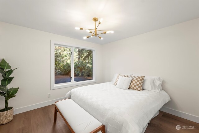 bedroom featuring dark wood-style floors, baseboards, and an inviting chandelier