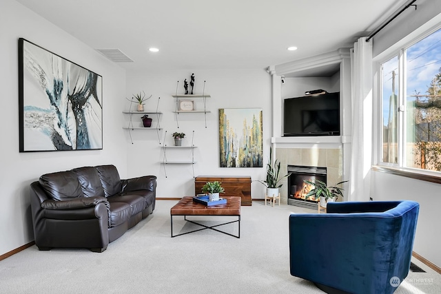 carpeted living room featuring a tiled fireplace and a wealth of natural light