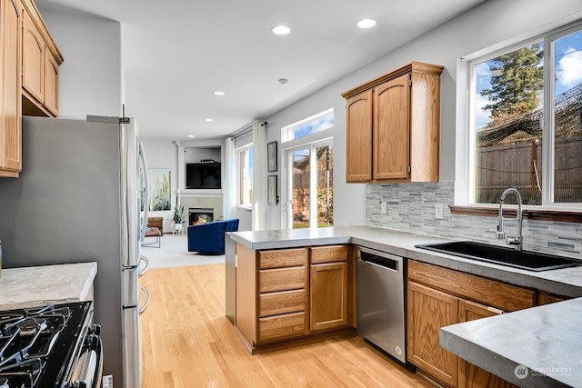 kitchen featuring a wealth of natural light, sink, stainless steel dishwasher, and light hardwood / wood-style flooring