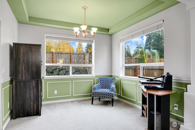 sitting room with a raised ceiling, carpet flooring, and an inviting chandelier