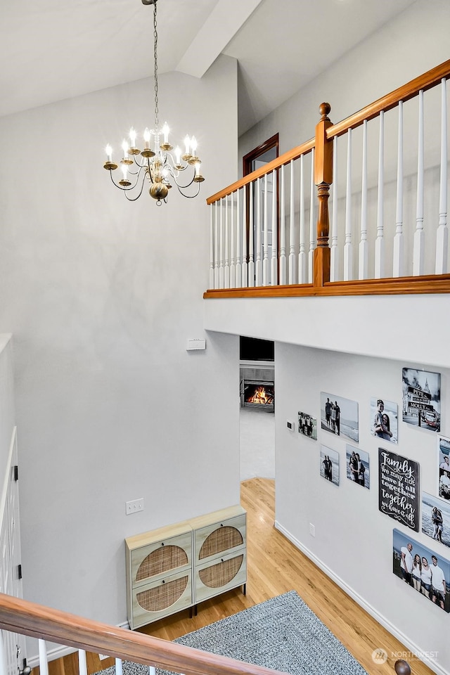 staircase with hardwood / wood-style floors, lofted ceiling, and a notable chandelier