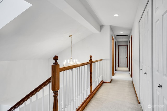 hall featuring light carpet and an inviting chandelier