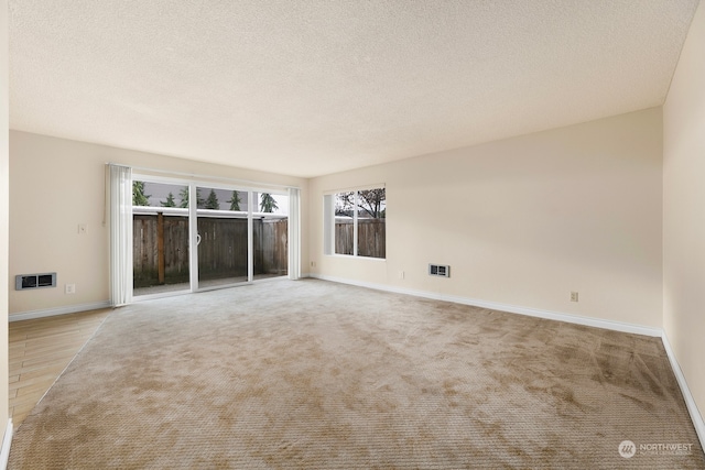 carpeted empty room with a textured ceiling