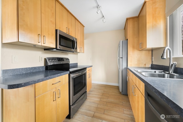 kitchen featuring stainless steel appliances, track lighting, and sink