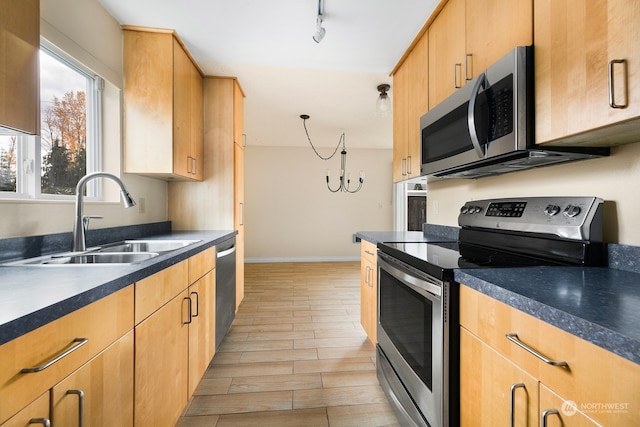 kitchen featuring sink, stainless steel appliances, a notable chandelier, track lighting, and light wood-type flooring