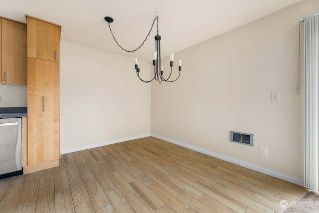 unfurnished dining area with light hardwood / wood-style flooring and an inviting chandelier