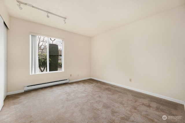 carpeted spare room featuring baseboard heating and track lighting