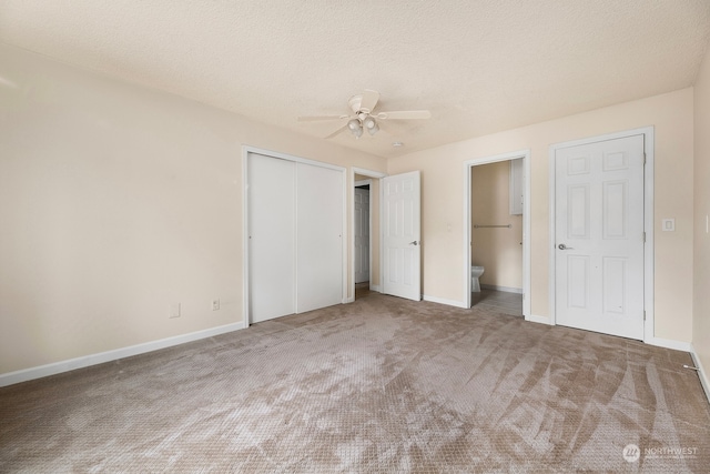 unfurnished bedroom featuring a textured ceiling, connected bathroom, carpet floors, and ceiling fan