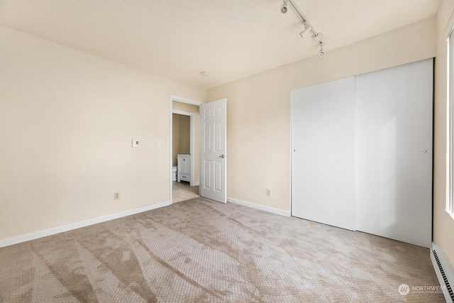 5021 Ripley Ln N Unit 112, Renton, WA 98056 - unfurnished bedroom featuring a baseboard radiator, carpet flooring, rail lighting, a closet, and baseboards