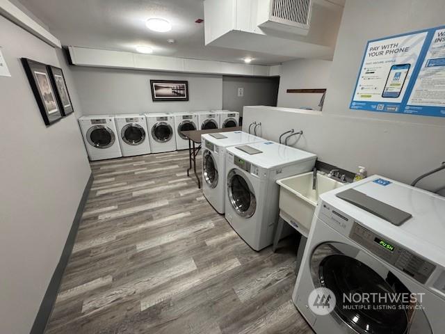 laundry room featuring separate washer and dryer, sink, and dark hardwood / wood-style flooring