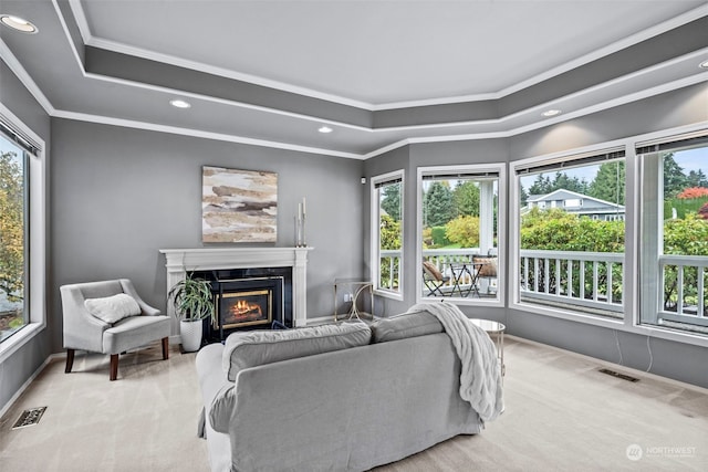 living room with crown molding, a fireplace, a wealth of natural light, and light colored carpet