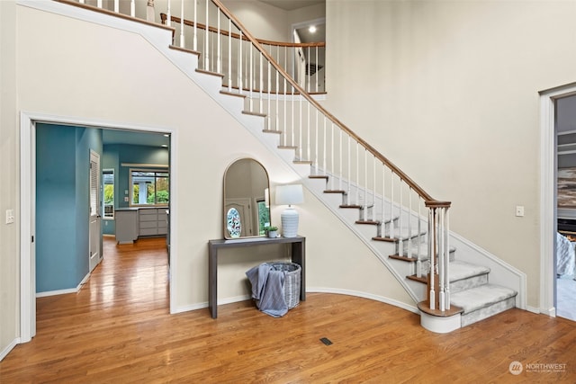 stairway with hardwood / wood-style flooring and a towering ceiling