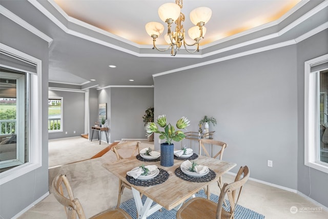 carpeted dining space with a chandelier, a tray ceiling, and ornamental molding