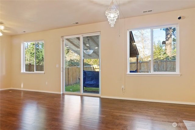 spare room featuring an inviting chandelier and dark hardwood / wood-style floors