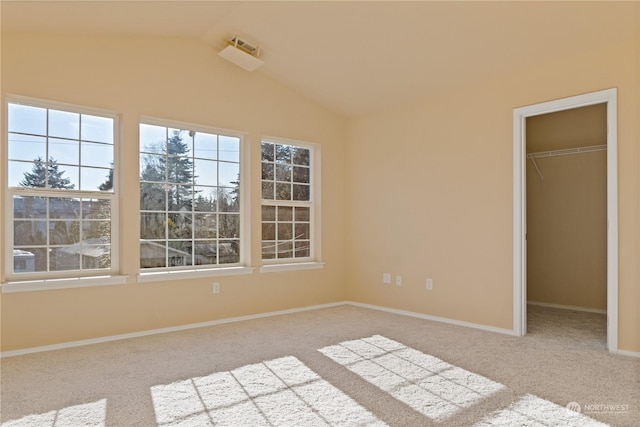 unfurnished bedroom featuring a spacious closet, vaulted ceiling, a closet, and carpet