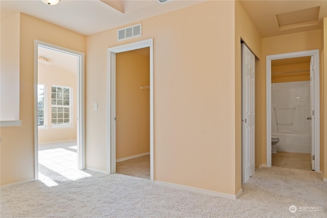 unfurnished bedroom with light carpet, a closet, and ensuite bathroom