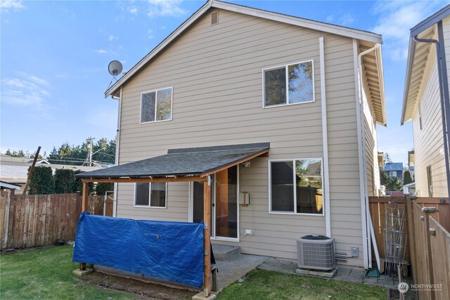 rear view of property featuring central AC and a yard