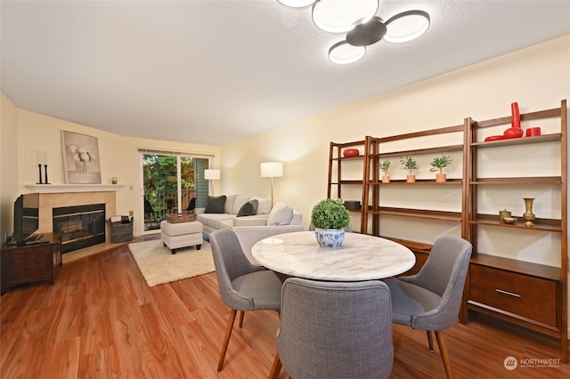 dining room featuring hardwood / wood-style floors, a fireplace, and a textured ceiling