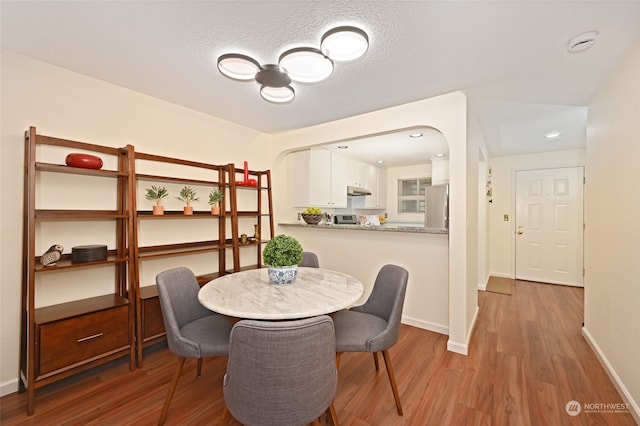 dining room featuring wood-type flooring and a textured ceiling