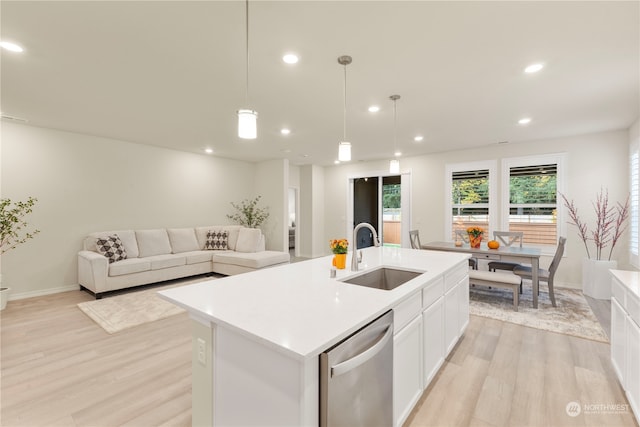 kitchen with sink, light wood-type flooring, stainless steel dishwasher, a kitchen island with sink, and pendant lighting