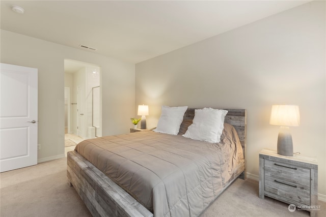 bedroom with connected bathroom and light colored carpet