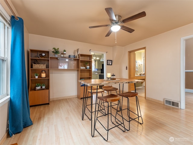 kitchen featuring ceiling fan, light wood-type flooring, and a breakfast bar area