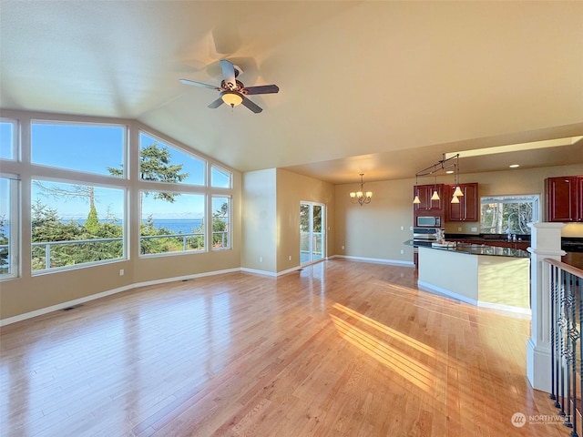 unfurnished living room featuring ceiling fan with notable chandelier, light hardwood / wood-style flooring, and lofted ceiling