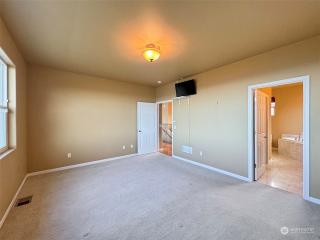 unfurnished bedroom with connected bathroom and light carpet