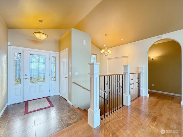 foyer entrance with a wealth of natural light, hardwood / wood-style flooring, a chandelier, and vaulted ceiling