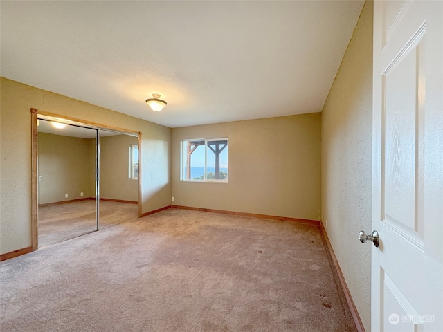 unfurnished bedroom featuring light colored carpet and a closet