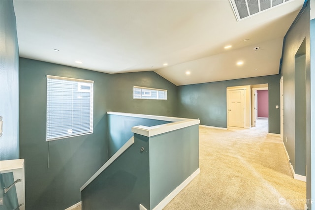 hallway featuring lofted ceiling and light carpet