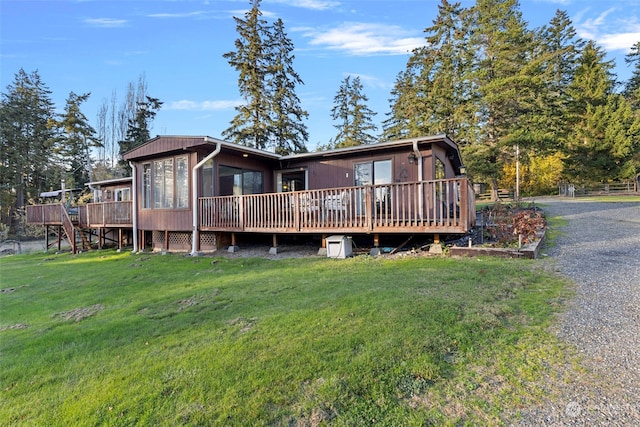 rear view of property with a wooden deck and a yard