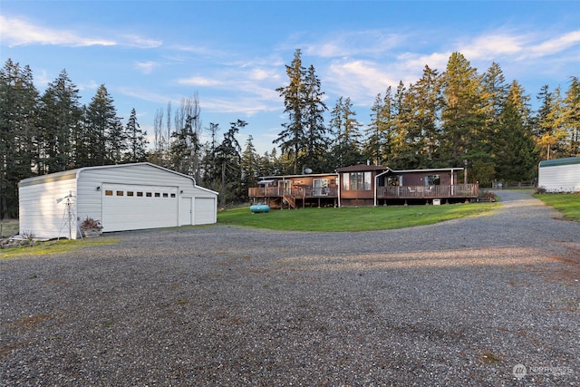 view of front of property featuring a front yard, a deck, a garage, and an outdoor structure