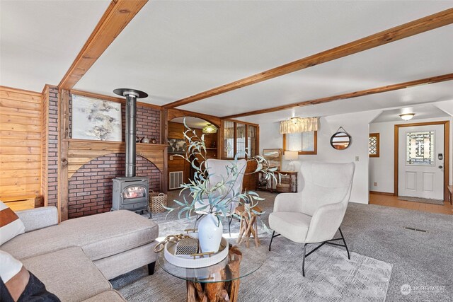 living room featuring a wood stove, wood walls, and plenty of natural light