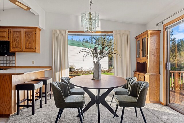 dining room with an inviting chandelier, vaulted ceiling, and light colored carpet