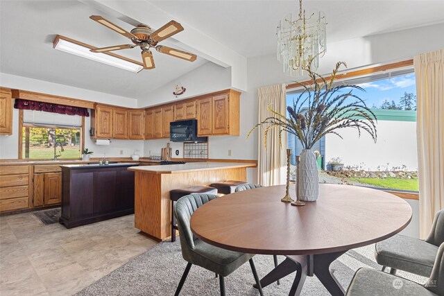 kitchen with a kitchen bar, vaulted ceiling with beams, a kitchen island, and ceiling fan with notable chandelier