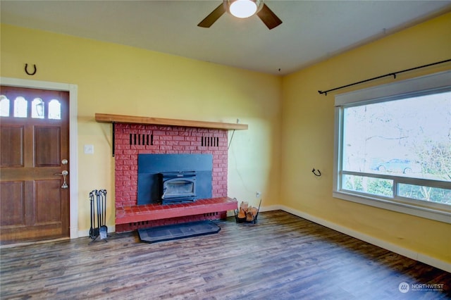 living room featuring hardwood / wood-style flooring, ceiling fan, a wood stove, and a wealth of natural light