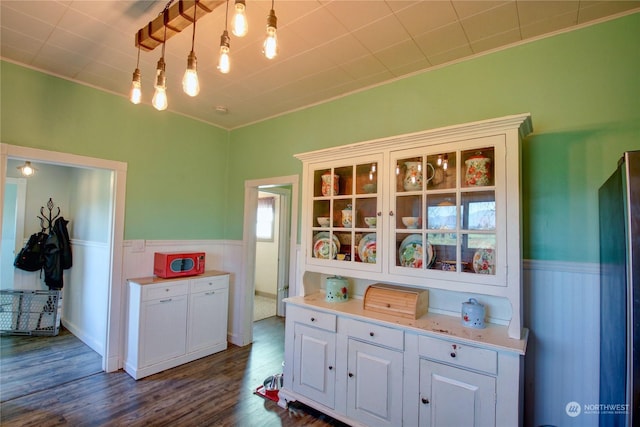 kitchen featuring dark hardwood / wood-style flooring, white cabinetry, hanging light fixtures, and crown molding