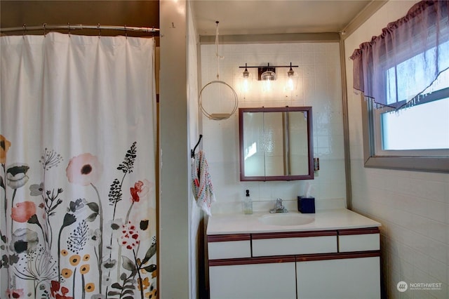 bathroom featuring a shower with curtain, vanity, and tile walls