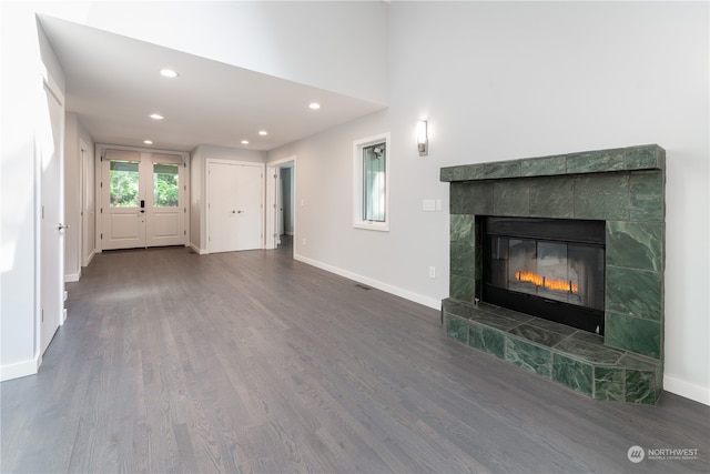 unfurnished living room with a tiled fireplace and dark hardwood / wood-style flooring