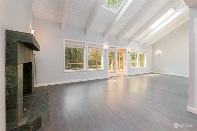 unfurnished living room featuring a stone fireplace, dark wood-type flooring, high vaulted ceiling, a skylight, and beam ceiling