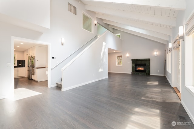 unfurnished living room with high vaulted ceiling, beamed ceiling, and dark hardwood / wood-style floors