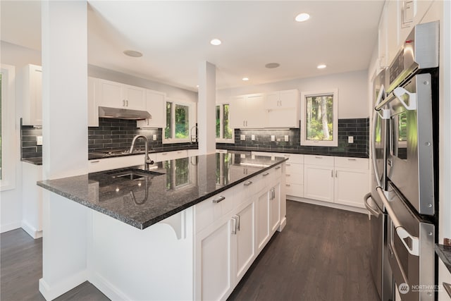 kitchen featuring white cabinets, dark hardwood / wood-style floors, dark stone countertops, and decorative backsplash