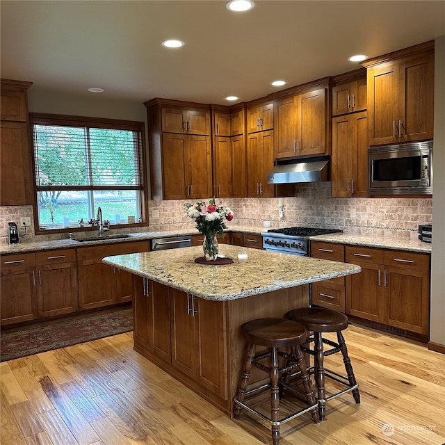 kitchen with stainless steel appliances, sink, light hardwood / wood-style flooring, a center island, and a breakfast bar area