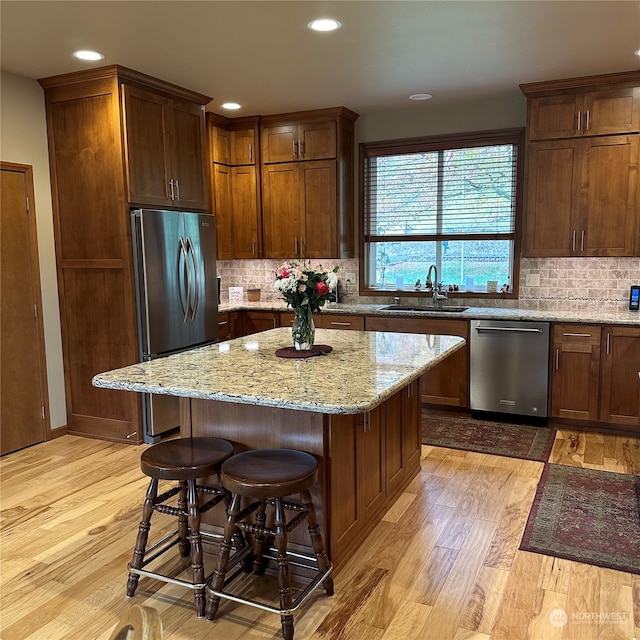 kitchen with stainless steel appliances, sink, a center island, light hardwood / wood-style floors, and a breakfast bar area