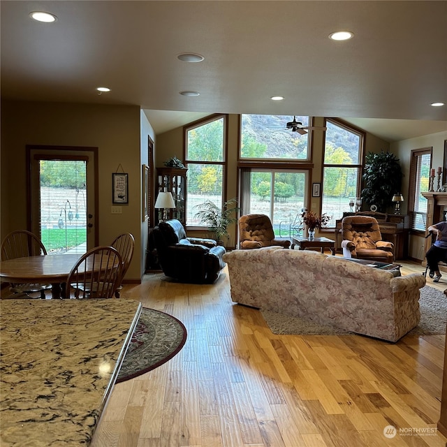 living room featuring light hardwood / wood-style floors, vaulted ceiling, and ceiling fan