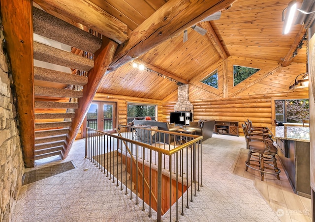 interior space with light hardwood / wood-style floors, wooden ceiling, rustic walls, high vaulted ceiling, and beamed ceiling