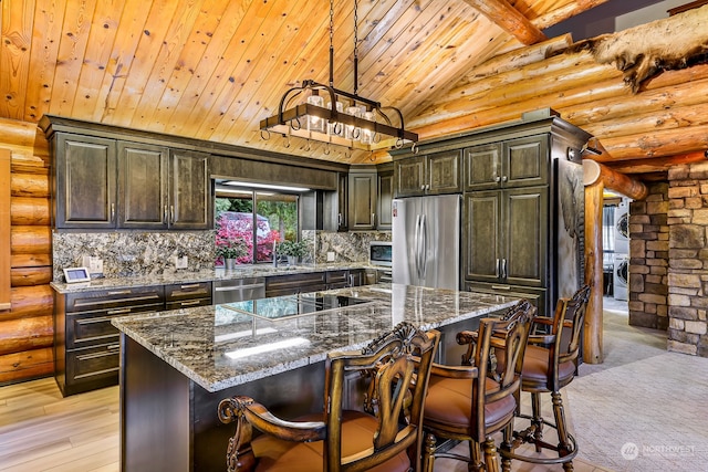 kitchen with log walls, appliances with stainless steel finishes, light hardwood / wood-style floors, stacked washer / drying machine, and a center island